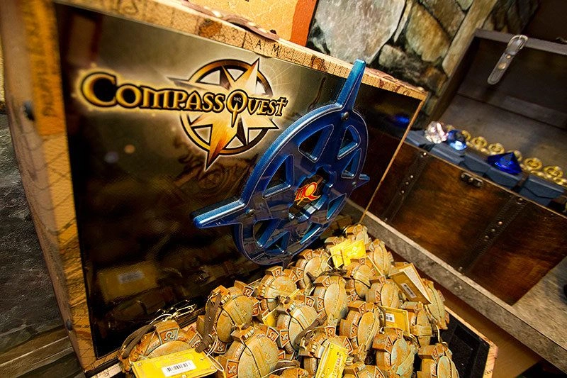 An open chest filled with kingdom compasses with the CompassQuest logo on the inside of the lid